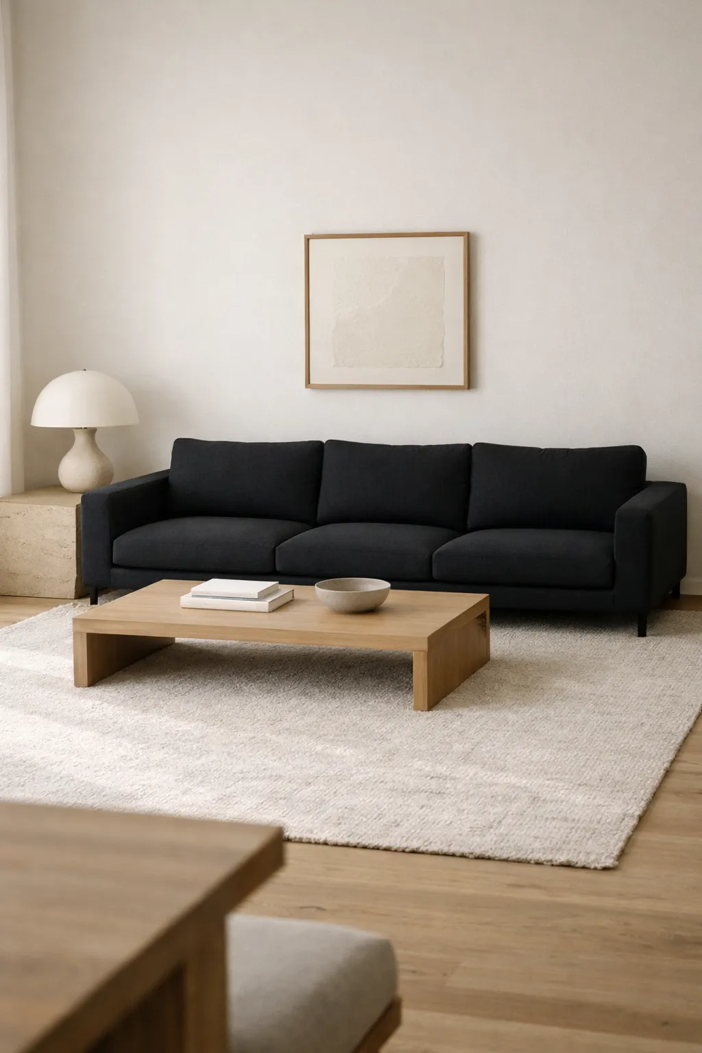 A minimalist living room with a black sofa, clean lines, neutral textures, and uncluttered modern styling.