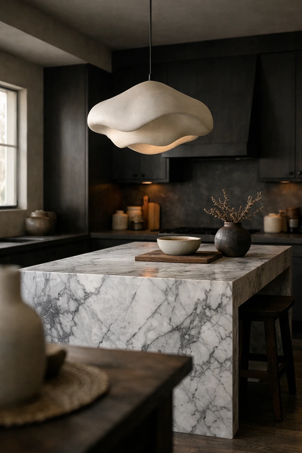Large sculptural pendant light above a dark kitchen island